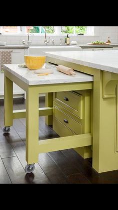 a kitchen island with a marble top and two drawers on casteors in the center