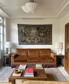 a living room filled with furniture and a large tapestry hanging on the wall above it