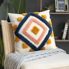 a white couch with a colorful pillow on top of it next to a book shelf