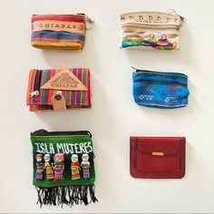 four small purses are lined up on a white surface, each with different designs and colors