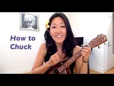 a woman holding an ukulele in her right hand and smiling at the camera