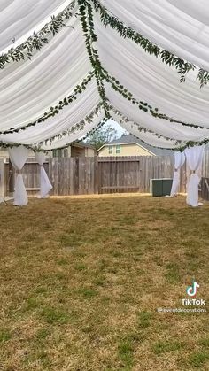 an outdoor wedding venue with white drapes and greenery