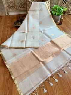 An exquisite pure 100% silk organza/kora benarasi saree in off white with copper & silver alfi buta (floral motif) woven throughout the six yards, along with a sleek golden border on either side. This saree is very stylish and classy, especially because of its simplicity and grace. The alfi (technique in Benaras weaving using two colored yarns) buta looks so stunning with the silver and copper zari as it keeps alternating with each motif. The pallu has a solid copper zari weaving. The fabric White Tussar Silk Saree For Diwali, White Cotton Silk Traditional Wear With Zari Weaving, White Tussar Silk Traditional Wear With Self Design, Diwali White Tussar Silk Dupatta, White Cotton Silk Traditional Wear For Diwali, White Handloom Tussar Silk Dupatta, White Tissue Silk Traditional Wear With Zari Work, White Traditional Wear With Sheer Dupatta In Tissue Silk, White Cotton Silk Dupatta For Festivals