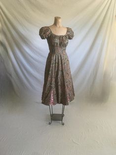 1950s handmade dress pull over w/side zip square neck w/pleated 'puffy' short sleeves pleated bust creates lots of room wide waist band unlined paisley print squiggly flocking over print circle skirt w/pink tulle panels good vintage condition, light wear measures, lying flat, sleeve-6 1/2" chest-17" plus 8" extra  (and a bit more) back pit to pit-16 1/2" waist-11 1/2" length from top shoulder to top of waist band-12" waist band top to bottom width-2 3/4" to 3" total length-44"     We do not offe Fitted Square Neck Vintage Dress For Garden Party, Square Neck Retro Vintage Dress, 1950s Style Fitted Tea Length Vintage Dress, Fitted 1950s Vintage Dress For Garden Party, Vintage Ruched Dress For Garden Party, Fitted Lined Vintage Dress For Garden Party, Vintage Square Neck Dress For Garden Party, Fitted Vintage Dress Lined For Garden Party, Fitted Vintage Dress With Ruffles And Square Neck