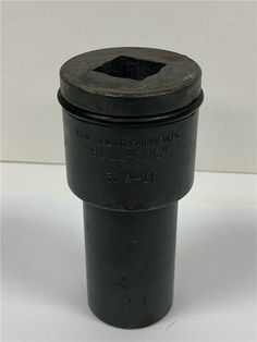 an old black metal object on a white surface