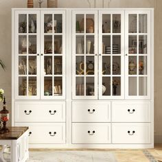 a white china cabinet with glass doors and drawers in a living room or dining room