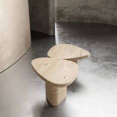 two wooden benches sitting on top of a cement floor next to a round metal object