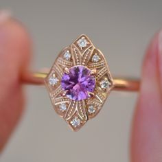 a close up of a person holding a ring with a purple stone in the middle