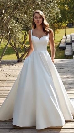 a woman in a white wedding dress standing on a wooden deck