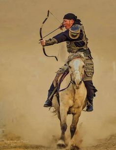 a man riding on the back of a white horse while holding a bow and arrow