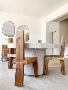 a marble table and two wooden chairs in a room with mirrors on the wall above it