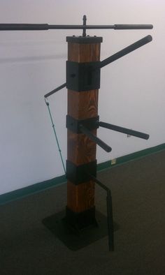 a tall wooden pole with metal bars attached to it's sides in front of a white wall