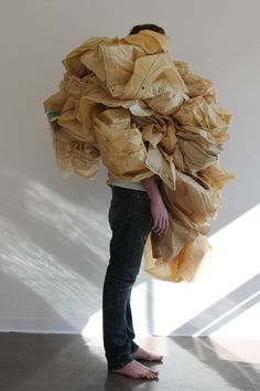 a man is standing in front of a white wall holding a large piece of paper