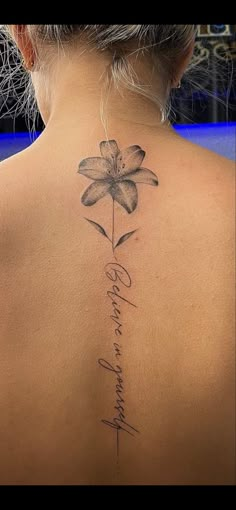 the back of a woman's neck with a flower tattoo on her left side