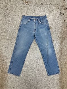 a pair of blue jeans sitting on top of a cement floor next to a wall