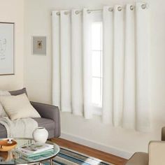 a living room filled with furniture and a window covered in white drapes next to a coffee table