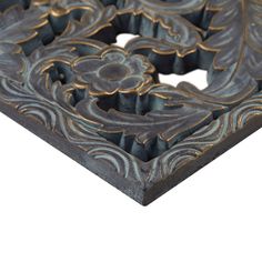 an intricately designed piece of wood with gold and black designs on the edges, against a white background