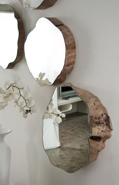 three mirrors hanging on the wall with flowers in vases next to them and one is empty