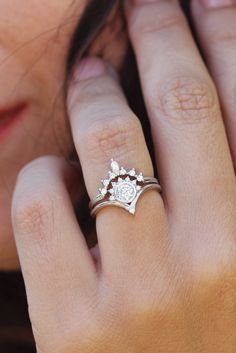 a close up of a person's hand with a ring on their finger and an engagement ring in the other hand