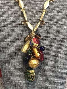 Beautiful Italian Murano beads are fashioned into a decorative statement cluster that is the centerpiece of this necklace.  The drop of beads measures 3 inches long by about 1 1/2 inches wide.  The necklace is 18 inches long.  There are smaller glass beads amongst the vibrant Murano beads.  There is a gold filled hook and gold filled findings. Gold Beaded Dangle Necklaces For Party, Gold Beaded Necklaces For Celebration, Party Gold-tone Necklace With Gold Beads, Costume Jewelry Necklaces With Dangling Beads For Parties, Gold Metal Beaded Necklace With Large Beads, Gold Metal Beaded Necklaces With Large Beads, Gold Beaded Necklace With Large Metal Beads, Gold Dangle Jewelry With Large Beads, Party Necklaces With Colorful Beads In Gold