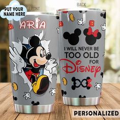 two mickey mouse tumblers sitting on top of a wooden table next to each other