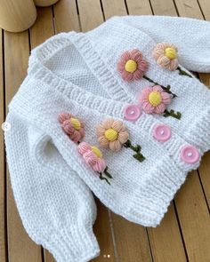 a knitted sweater with flowers on the front and back, sitting on a wooden floor