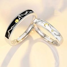 two wedding rings with black and white enamel inlays on each ring, set against a light colored background