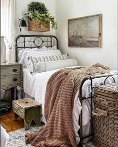 a bedroom with a bed, wicker basket and painting on the wall above it