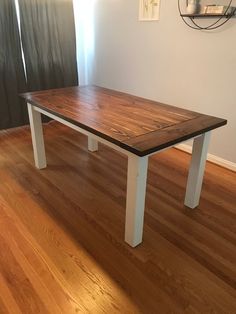 a wooden table sitting on top of a hard wood floor next to a white wall