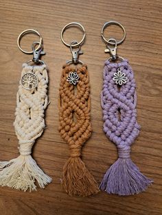 three key chains with tassels on top of a wooden table