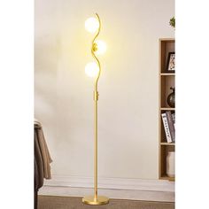 a floor lamp with three lights on it in a room next to a book shelf