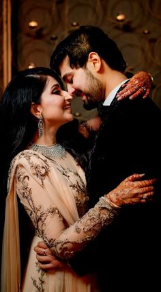 a man and woman embracing each other in front of a wall with lights on it