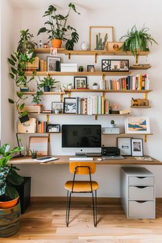 a home office with plants and bookshelves on the wall above the computer desk