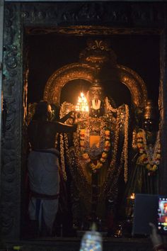 a man standing in front of a statue with candles on it's face and hands