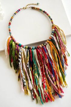 a multicolored necklace is displayed on a white surface