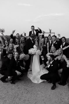 a large group of people posing for a photo with their hands up in the air