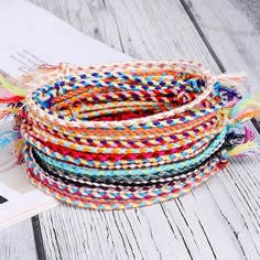 multicolored woven bracelets with tassels on top of an open book