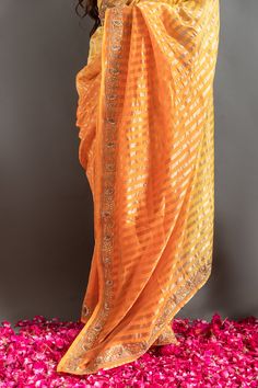 Yellow and orange saree with an ombre woven stripe base highlighted by zardozi embroidery. Comes with matching embroidered blouse.
Components: 2
Pattern: Embroidered
Type Of Work: Zardozi, Gotapatti
Neckline: Round
Sleeve Type: Half
Fabric: Tissue
Color: Orange,Yellow
Other Details: 
Woven zari stripes
Placed embroidery
Occasion: Mehendi and Haldi,Sangeet - Aza Fashions Traditional Orange Art Silk Pre-draped Saree, Festive Orange Pre-draped Saree, Traditional Orange Pre-draped Saree With Zari Weaving, Unstitched Orange Pre-draped Saree For Puja, Orange Pre-draped Saree With Dupatta For Festivals, Designer Orange Dupatta With Resham Embroidery, Designer Orange Dupatta For Festivals, Orange Banarasi Silk Pre-draped Saree For Diwali, Festive Orange Pre-draped Saree With Zari Weaving