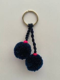 two pom - poms hanging from a metal ring on a white table top