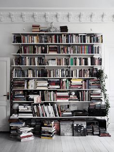 a bookshelf filled with lots of books next to a white door in a room