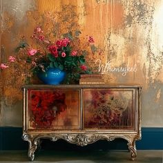 a vase filled with flowers sitting on top of a wooden dresser next to a wall