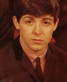 a young man in a suit and tie looking at the camera with an intense look on his face