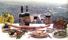 a table topped with lots of food and bottles of wine on top of a mountain