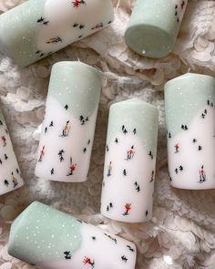 several white candles with designs on them sitting on a doily covered tablecloth, next to each other