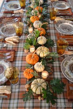 a long table is set with pumpkins and gourds