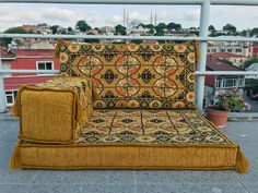 a yellow couch sitting on top of a cement floor next to a potted plant