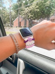 a person wearing a bracelet and watch on their wrist in a car with the sunroof behind them