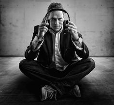 a man sitting on the floor with headphones in his ears and holding up two hands