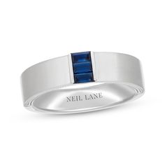 a white gold ring with a blue sapphire stone in the center and an inscription that reads neil lane