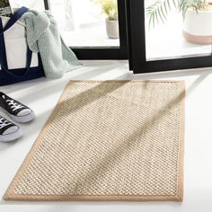 a pair of sneakers sitting on top of a white floor next to a door mat